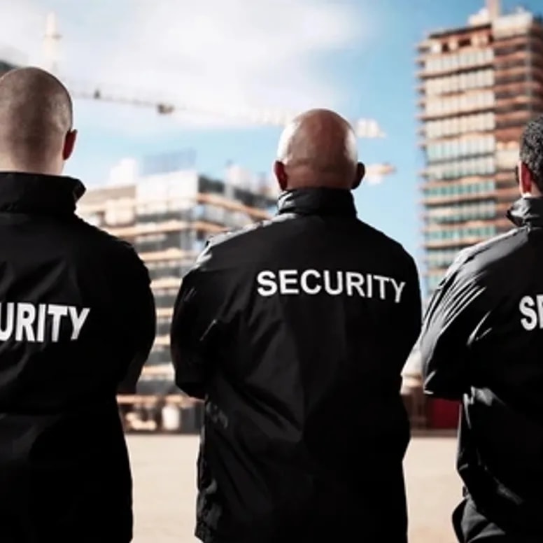 Three security personnel in black jackets surveying an incident site